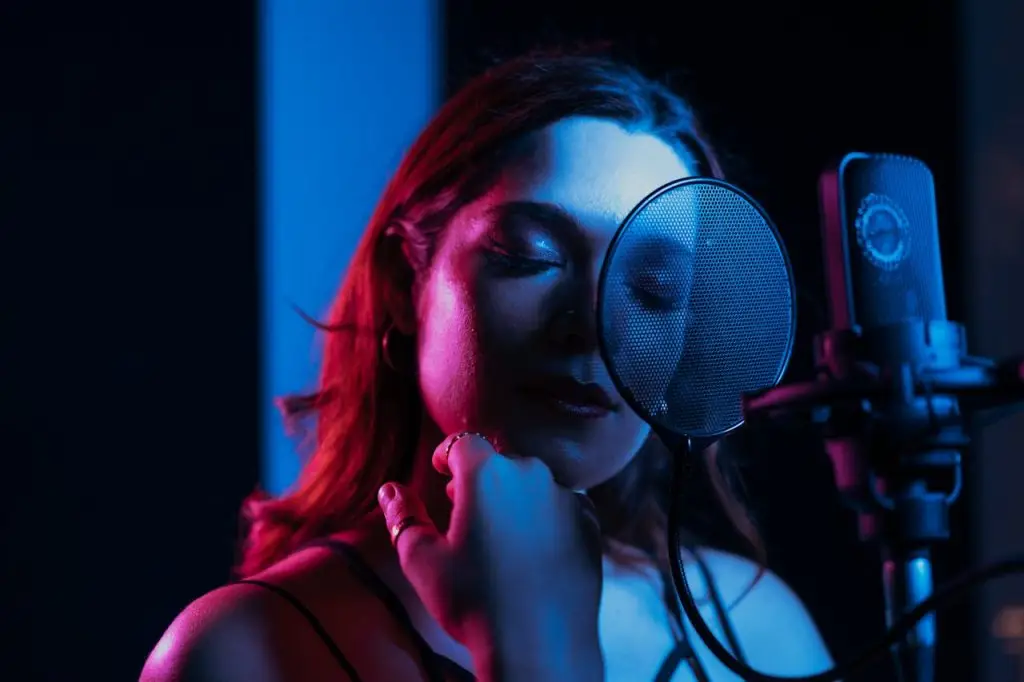 A captivating portrait of a female singer with closed eyes performing in a dimly lit recording studio.